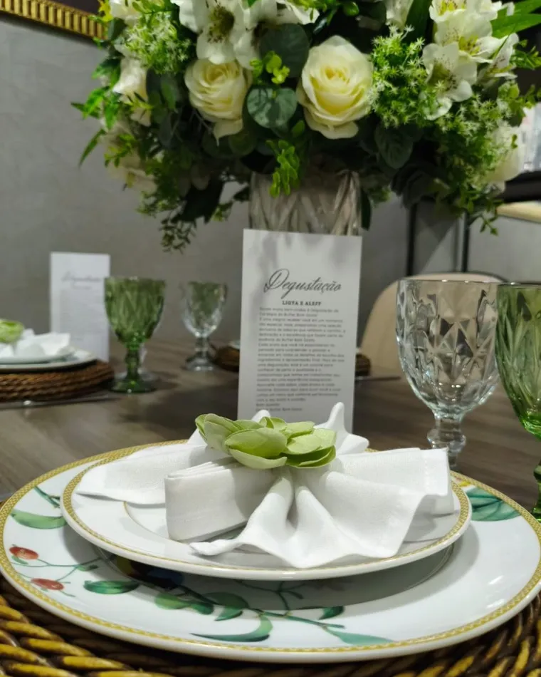 Mesa de degustação com arranjo de flores, louça branca e taças de cristal