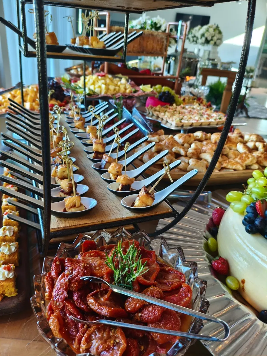 Coquetel volante com tábuas e finger food em suportes dourados