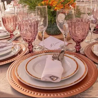 Detalhe de lugar posto com sousplat, prato de sobremesa e taça rosé