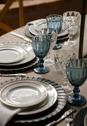 Lugar posto com sousplat azul, louça e taça de cristal