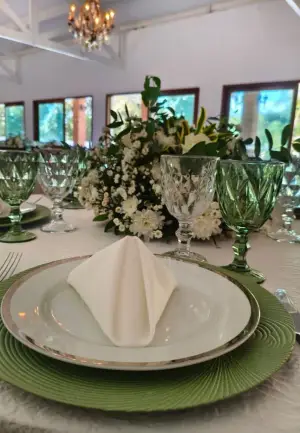 Lugar posto com sousplat verde, louça e taça de cristal